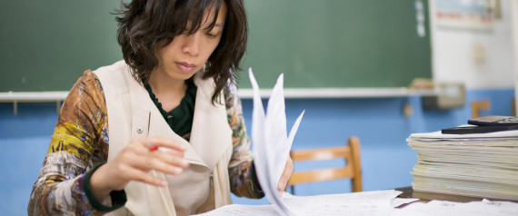 Teacher marks exam papers in classroom