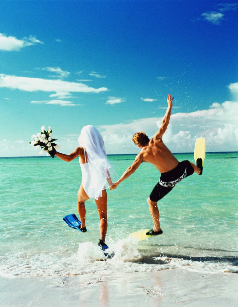 Bride and groom wearing flippers, running into sea (Enhancement)